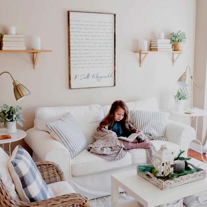 Little girl sitting on a white couch reading a book
